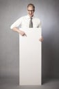 Laughing businessman pointing finger at white blank poster. Royalty Free Stock Photo