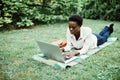 Calm to work outdoors. Young afro american student lying on grass taking notes on campus at college Royalty Free Stock Photo