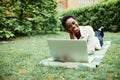 Surf in internet. Young afro american student lying on grass taking notes on campus at college Royalty Free Stock Photo