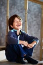 Laughing Caucasian boy, seven years old, sits on an interfloor wooden staircase at home. Royalty Free Stock Photo