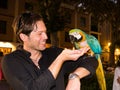 laughing caucasian handsome man in black shirt holds a parrot and feeds it