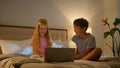 Laughing Caucasian happy children brother sister kids girl boy looking laptop screen in bedroom on bed evening watching Royalty Free Stock Photo