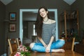 Laughing Caucasian young beautiful woman model with messy long hair in ripped blue jeans and striped t-shirt sitting on table