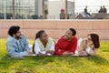 Laughing cheerful international millennial students rest after lessons, lie on grass in campus