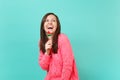 Laughing cheery young woman in knitted pink sweater looking up, holding watermelon lollipop isolated on blue turquoise