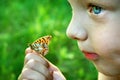 Laughing child. Butterfly sitting on the hand of a child. Child with a butterfly. Selective focus.