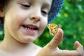 Laughing child. Butterfly sitting on the hand of a child. Child with a butterfly. Selective focus.