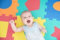 Laughing child on a colored rubber mat puzzle for playing foam with geometric figures