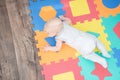 Laughing child on a colored rubber mat puzzle for playing foam with geometric figures