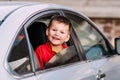 A laughing child looks out of an open car window Royalty Free Stock Photo