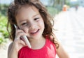 Laughing child in a red shirt speaking at phone outside Royalty Free Stock Photo