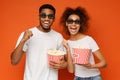 Laughing couple in 3d glasses holding buckets of popcorn