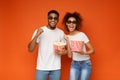 Laughing couple in 3d glasses holding buckets of popcorn