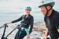 Laughing couple, helmet or electrical bike by sea in transportation, clean energy or sustainability travel bonding