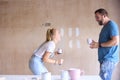 Laughing Couple Renovating Kitchen At Home Painting Tester Paint Colour Strips On Wall