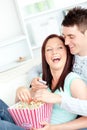 Laughing couple on sofa with popcorn and remote Royalty Free Stock Photo