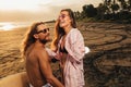 laughing couple standing near scooter on beach during sunset Royalty Free Stock Photo