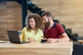 Laughing couple using laptop drinking coffee sitting in cafe.