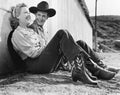 Laughing couple in western attire sitting on the ground Royalty Free Stock Photo