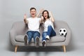Laughing couple woman man football fans cheer up support favorite team with soccer ball, showing thumbs up, clenching
