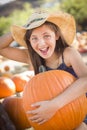 Laughing Cowgirl Holding A Large Pumpkin at the Pumpkin Patch