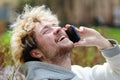 Laughing curly blond man enjoys a phone conversation with friends