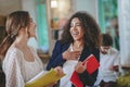 Laughing curly girl talking to another standing in profile, guy nearby Royalty Free Stock Photo