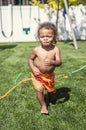 Laughing Cute little boy splashing through the sprinklers in the backyard