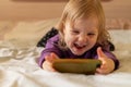 Laughing cute little girl gen Z using online app on mobile phone, browsing internet, playing video games, taking selfie Royalty Free Stock Photo