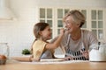 Laughing elderly granny and small grandchild painting noses with flour