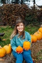 Laughing emotional young woman in witch hat holding pumpkins. Female selecting best pumpkins for Thanksgiving and