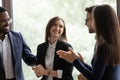 Diverse millennial colleagues meeting new female teammate in office