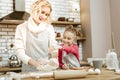 Laughing entertained mother mixing dough with her daughter