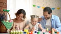 Laughing family painting eggs for Easter celebration having fun, happy childhood