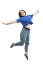 A laughing fat young girl in a blue tank top and jeans is emotionally jumping. Isolated on a white background. Full height. Royalty Free Stock Photo