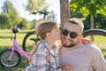 Laughing father and his daughter having fun together at the green park, relax and have fun together after cycling Royalty Free Stock Photo