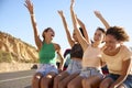 Laughing Female Friends Sitting On Hood Of Open Top Car On Road Trip Royalty Free Stock Photo