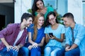 Laughing female influencer with mobile phone and group of young adult friends