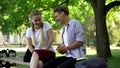 Laughing friends sitting on bench in park, telling extremely funny story, joke Royalty Free Stock Photo