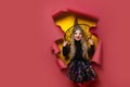 Laughing funny child girl in a witch costume of halloween looking, smiling and scares through a hole of red, yellow Royalty Free Stock Photo