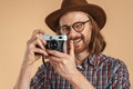 Laughing ginger man wearing eyeglasses and hat using retro camera Royalty Free Stock Photo