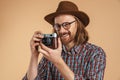 Laughing ginger man wearing eyeglasses and hat using retro camera Royalty Free Stock Photo
