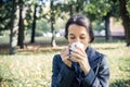 Laughing girl in an autumn part with a white cup of hot drink