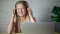 Laughing girl in headphones using laptop, e-learing, children using technology Royalty Free Stock Photo