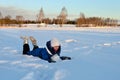 laughing girl lies in snow and plays with snow against background of winter nature. Happy girl enjoys snowy