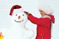 Laughing girl sculpts big snowman