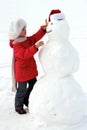 Laughing girl sculpts big snowman