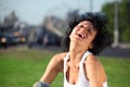 Laughing girl sits on lawn at road in city