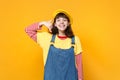 Laughing girl teenager in french beret denim sundress doing phone gesture like says call me back isolated on yellow