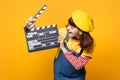 Laughing girl teenager in french beret, denim sundress looking on classic black film making clapperboard isolated on